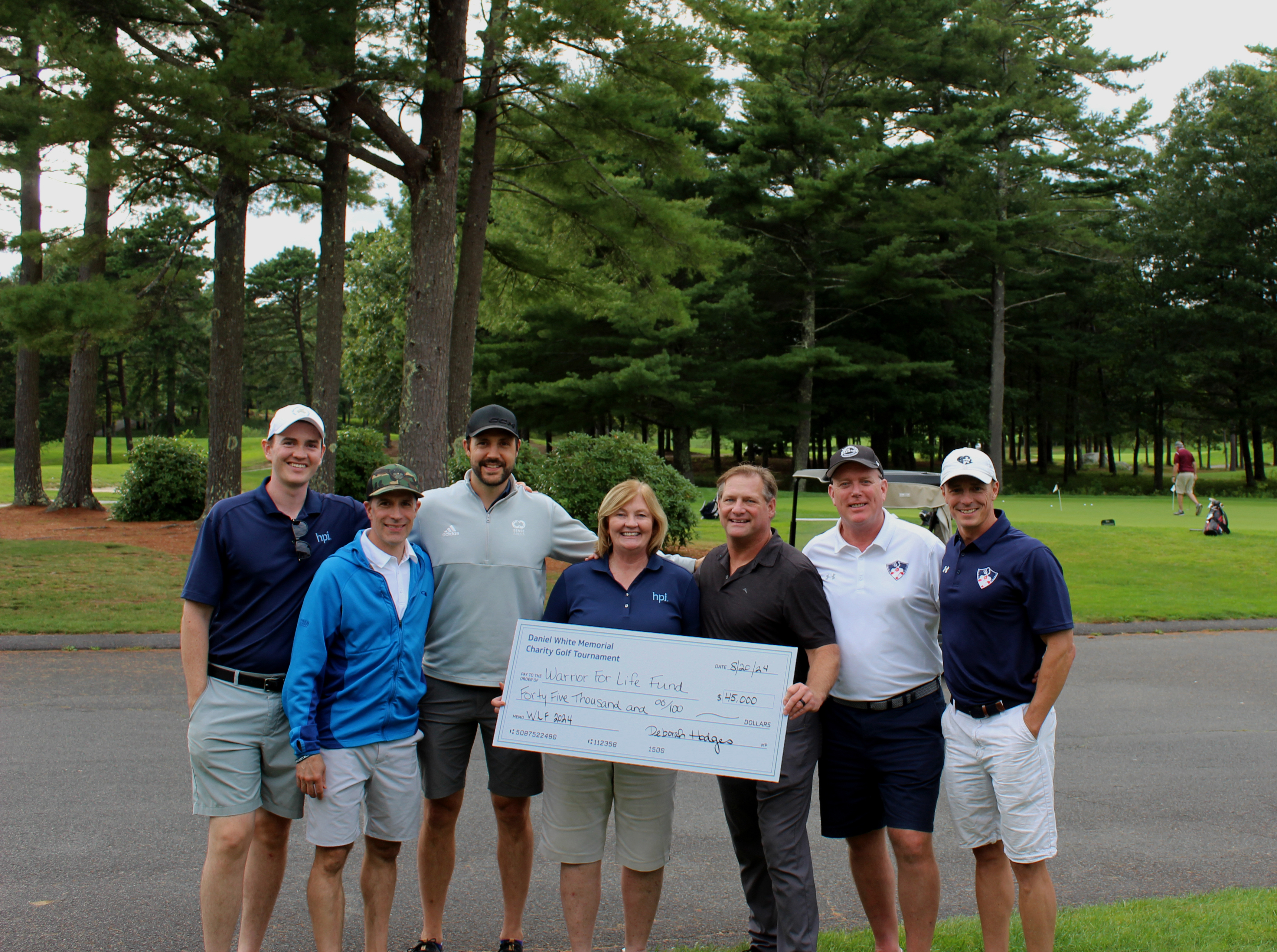 Golf tournament attendees holding a large donation check